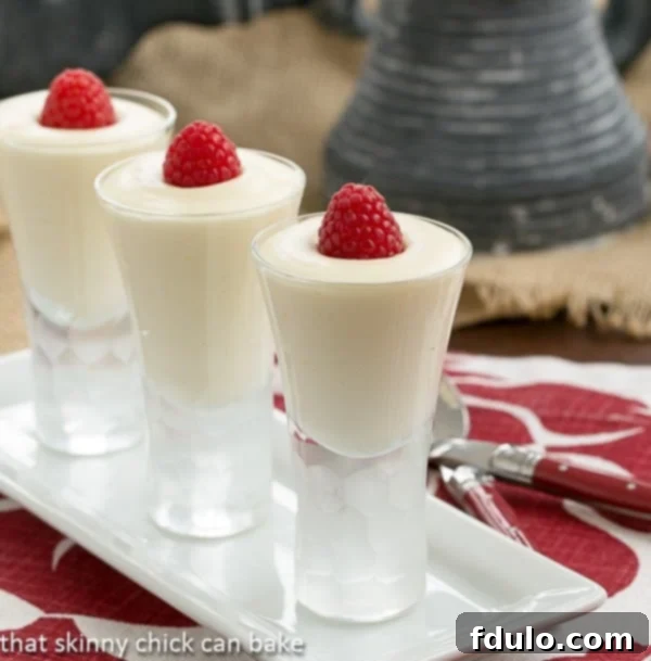 Dreamy White Chocolate Mousse spiked with Frangelico in decorative shot glasses topped with fresh raspberries for a festive touch.