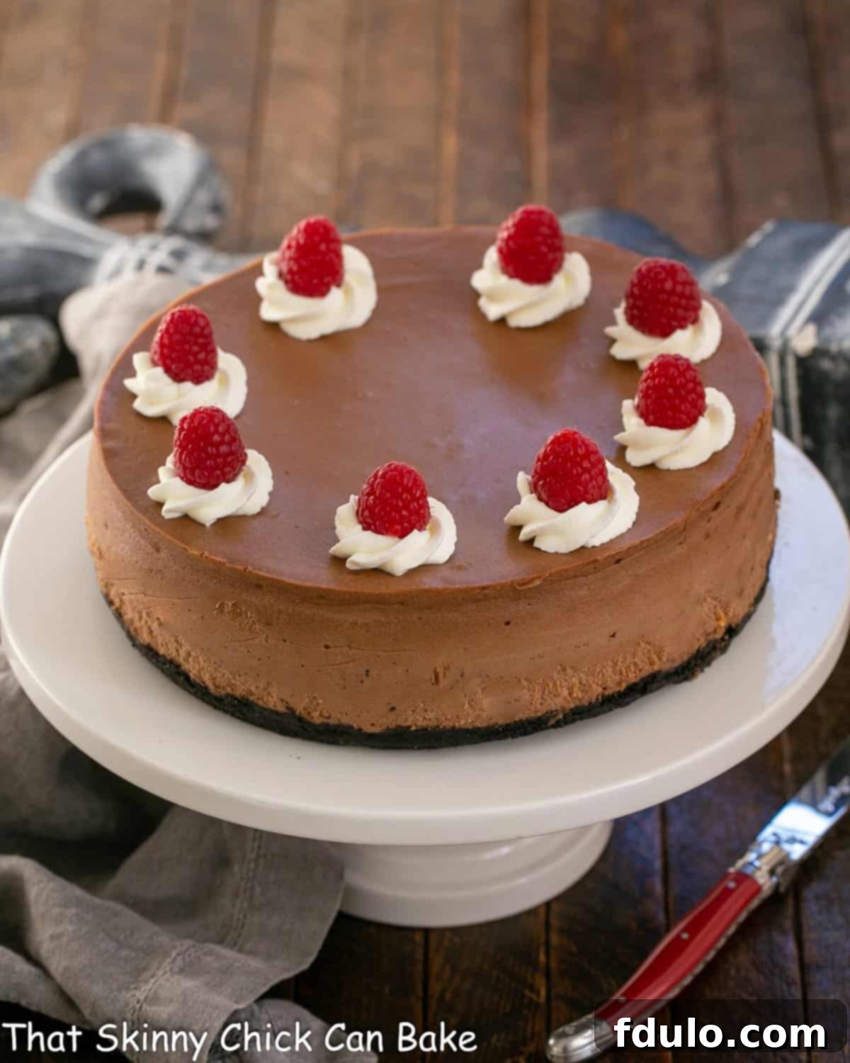 A stunning Chocolate Mascarpone Cheesecake sits elegantly on a white ceramic cake stand, inviting indulgence.