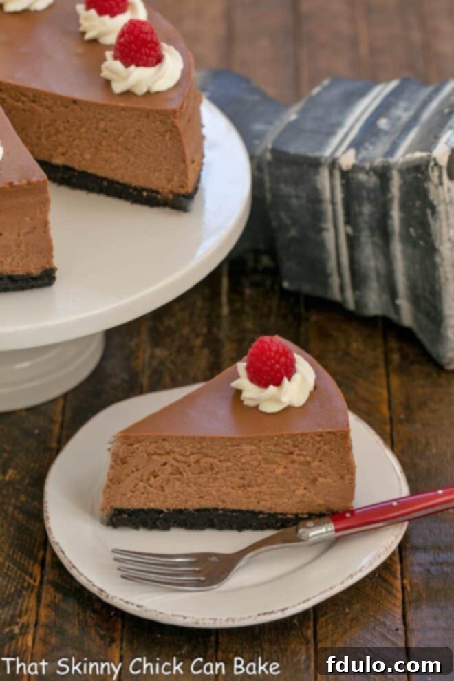 A perfectly sliced piece of Italian Cheesecake rests on a white plate, with the rest of the cheesecake on a cake stand in the background.