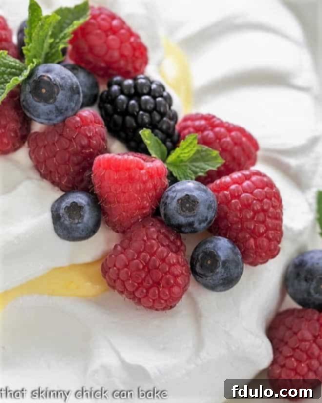Vibrant fresh berries and mint artfully arranged on top of a crisp meringue shell, ready for the lemon curd and whipped cream