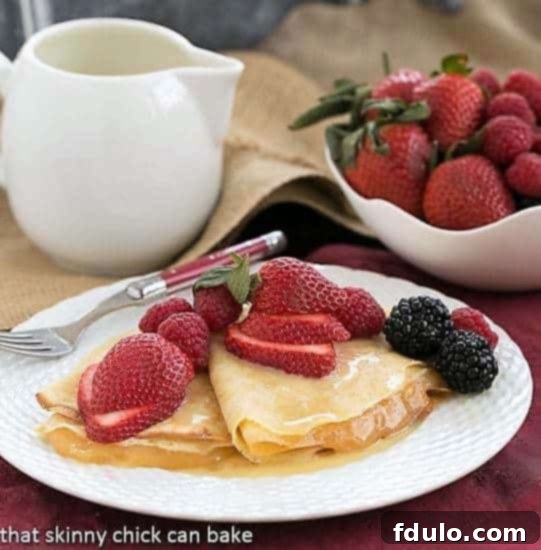 Butter and Rum Crêpes on a white plate topped with fresh berries, showcasing their elegant presentation.