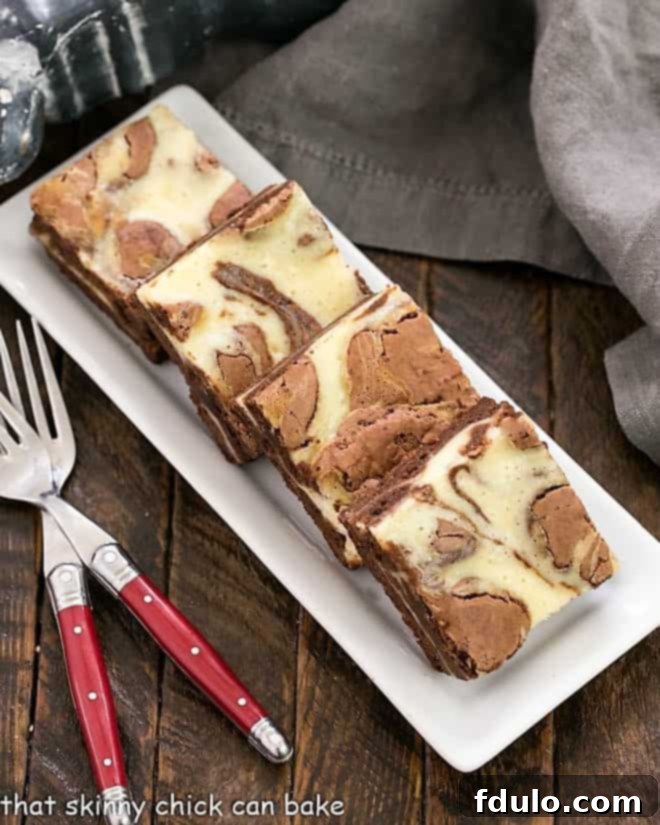 Overhead view of a tray of cheesecake brownies with two red handled forks.