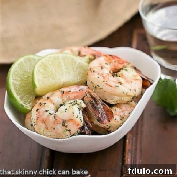 Margarita shrimp in a bowl with lime slices and fresh cilantro for garnish.