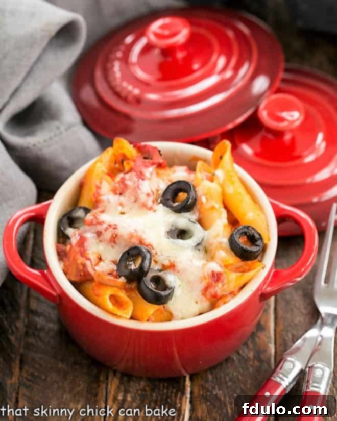 Overhead view of cheesy pasta bake in a small red crock.