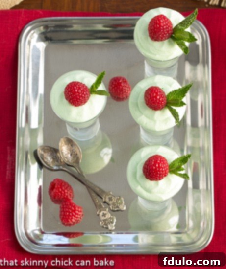 Grasshopper Mousse presented on a silver platter, with small serving spoons and fresh raspberries scattered around, viewed from an appealing overhead angle.