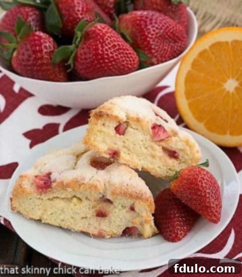 Golden-brown Strawberry Buttermilk Scones on a white plate, garnished with fresh, vibrant strawberries, ready to be enjoyed.