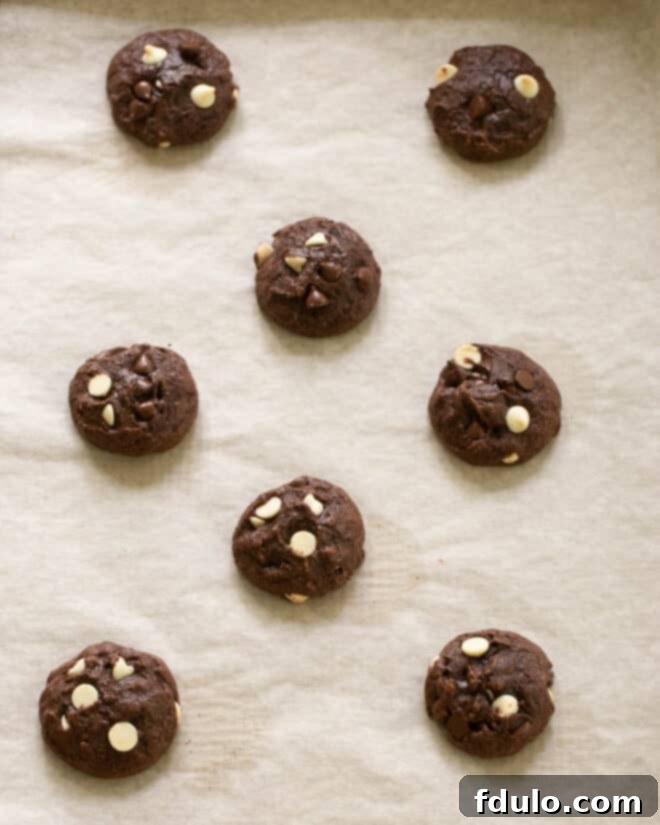 Brownie cookies baking on a parchment-lined sheet.