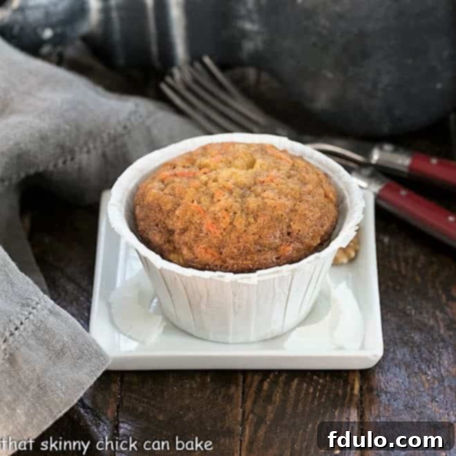 One perfectly baked carrot cake muffin on a small square white plate, ready to be enjoyed.