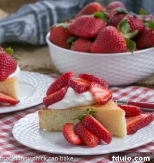 Elegant French Vanilla Sponge Cake with Berries and Cream A perfectly sliced French Visitandine Cake on a pristine white plate, crowned with vibrant mixed berries and a dollop of airy whipped cream, ready to be enjoyed.