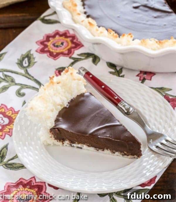 A slice of Coconut Crusted Chocolate Ganache Pie on a white plate with a red handled fork