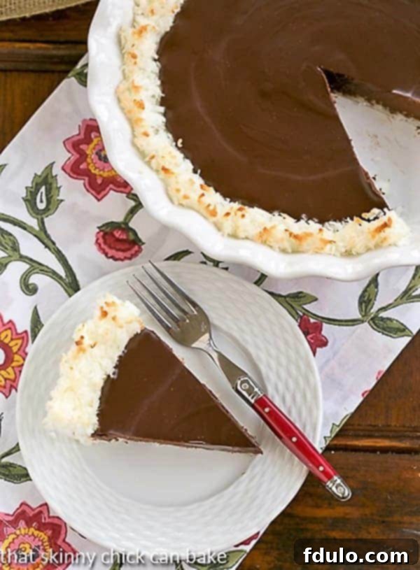 Coconut Crusted Chocolate Ganache Pie with a slice removed, showing the creamy chocolate filling and the textured coconut crust.
