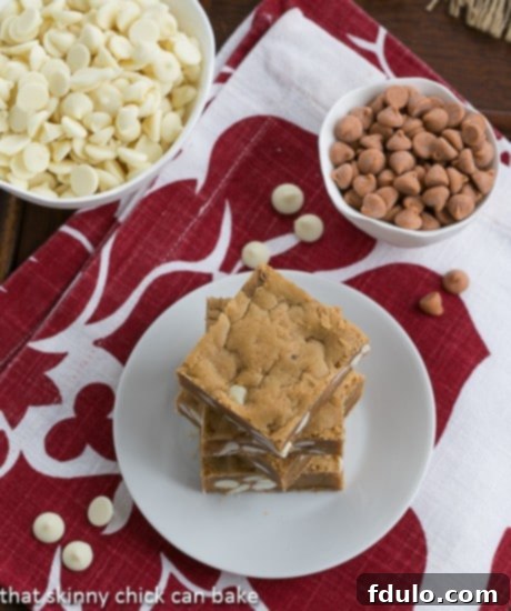 Overhead view of a stack of golden Butterscotch Blondies with visible white chocolate chips on a white plate, elegantly set on a festive red and white napkin.