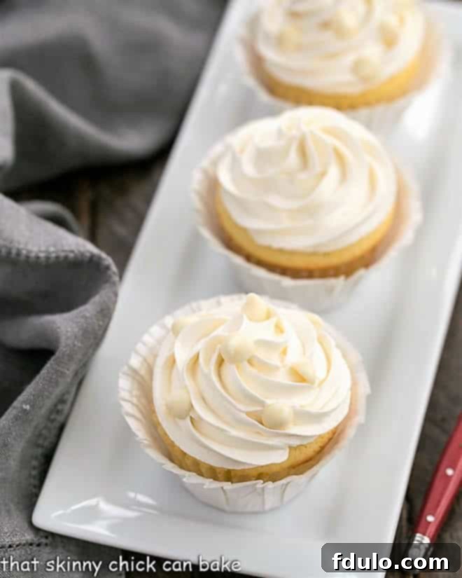 Ghirardelli Vanilyalı Cupcakeler, Beyaz Çikolatalı Swiss Meringue Kreması ile dikdörtgen seramik bir tepside.