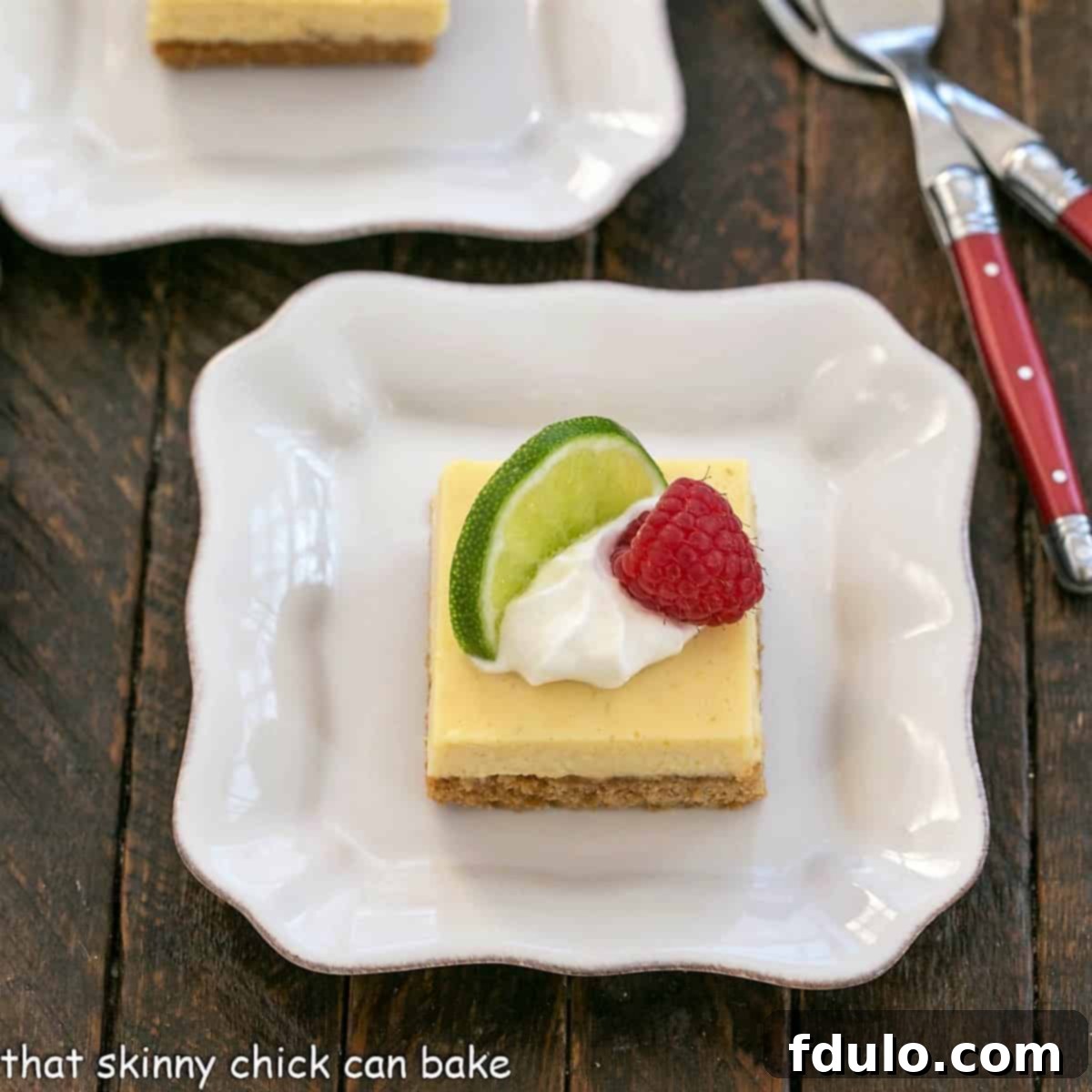 Overhead view of a key lime pie bar with a dollop of whipped cream, slice of lime and raspberry to garnish.