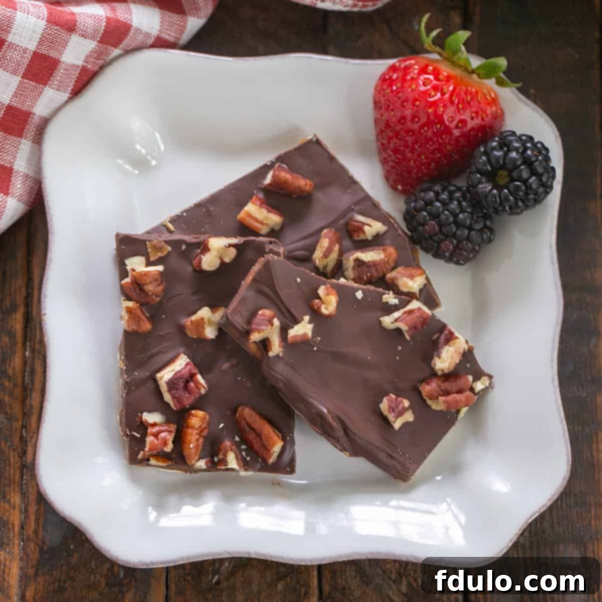 Matzo crack on a square white plate with berries, a delicious and easy to make dessert.