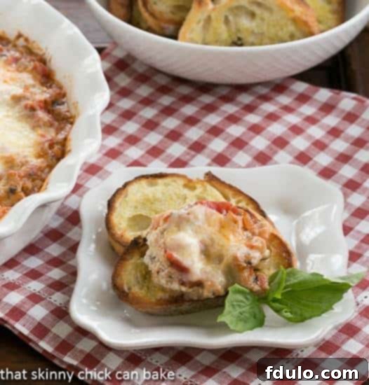A close-up of golden-brown Cheesy Lasagna Dip with Sausage, served on toasted baguette slices and garnished with fresh basil