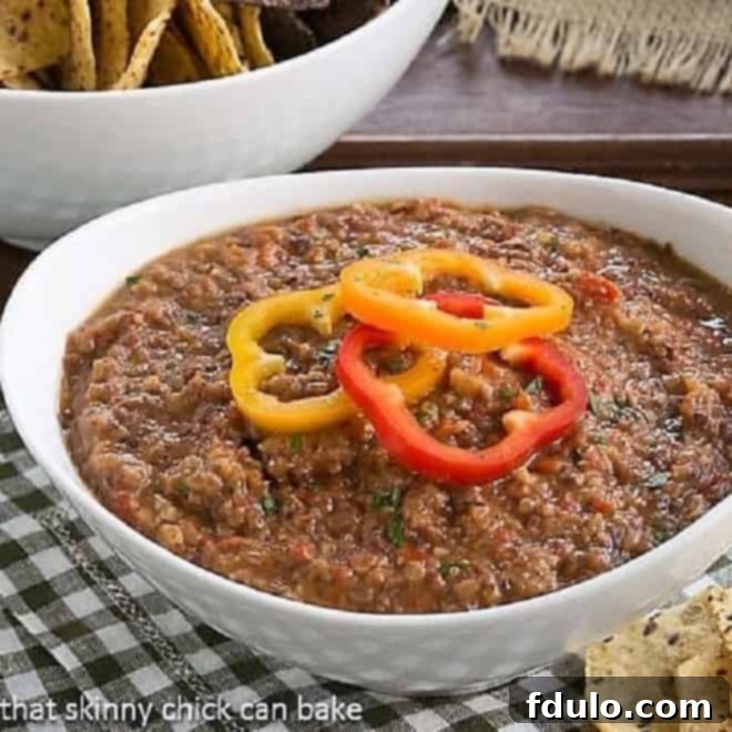 Smoky Black Bean Dip in a white bowl topped with fresh bell pepper rings