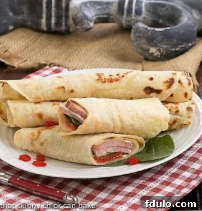 Potato Lefse - a delicious, versatile, Norwegian flatbread Potato Lefse sandwiches on a white serving plate, garnished with fresh herbs.