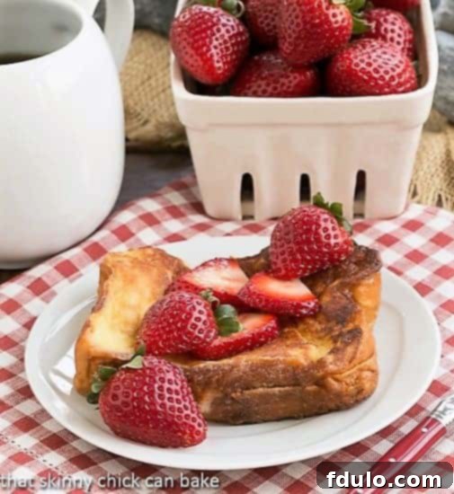 Decadent Strawberry Mascarpone Stuffed French Toast on a white plate, garnished with fresh strawberries and a light dusting of powdered sugar, ready to be enjoyed.