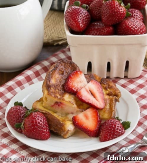 Strawberry Mascarpone Stuffed French Toast, expertly cut in half to reveal the creamy mascarpone and fresh strawberry filling, served elegantly with additional berry garnish.