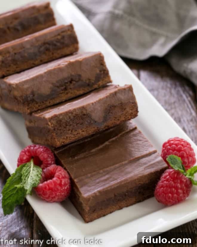 Decadent Infused Chocolate Brownies 3 A close-up shot of a tray of chocolate poke brownies, generously garnished with fresh raspberries, showcasing the rich texture and irresistible appeal of the dessert.