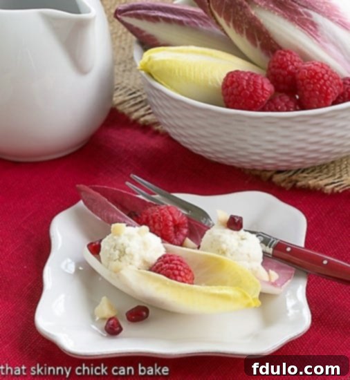Endive Cups with Blue Cheese, Raspberries and Macadamia Nuts elegantly arranged on a white plate, ready to be served as a gourmet appetizer.