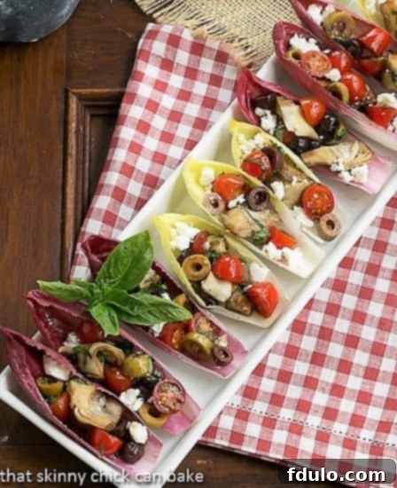 Mediterranean Endive Boats - a fun, bite-sized salad or appetizer A charming tray of Mediterranean Endive Boats resting on a festive red and white checked napkin, ready to be served.