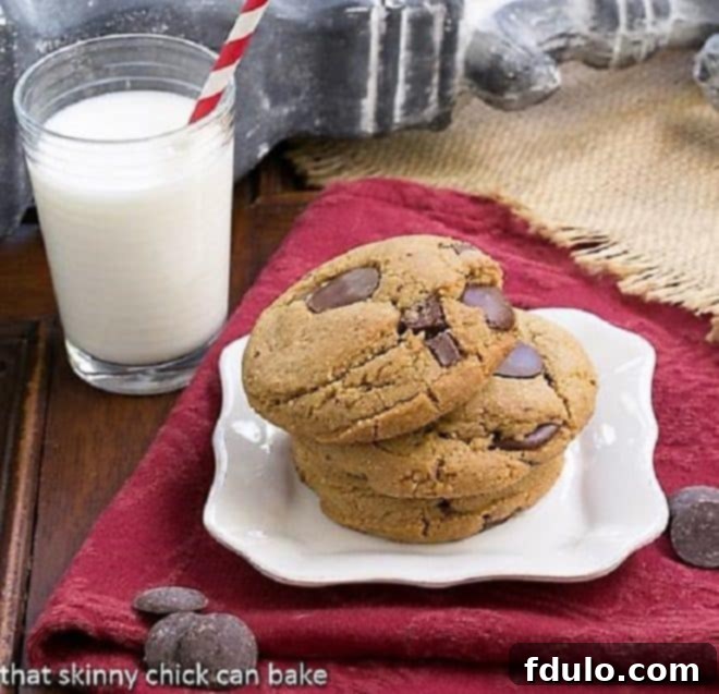 Jumbo Chocolate Chip Cookies - Big, chewy chocolate chip cookies with caramel undertones! Three perfectly baked jumbo chocolate chip cookies stacked on a white square plate, accompanied by a refreshing glass of milk.