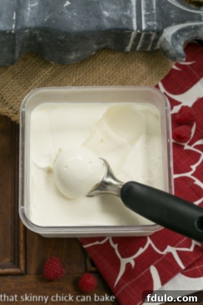 Homemade Cheesecake Ice Cream with a creamy texture in an OXO container, ready to be scooped and enjoyed in a sundae.