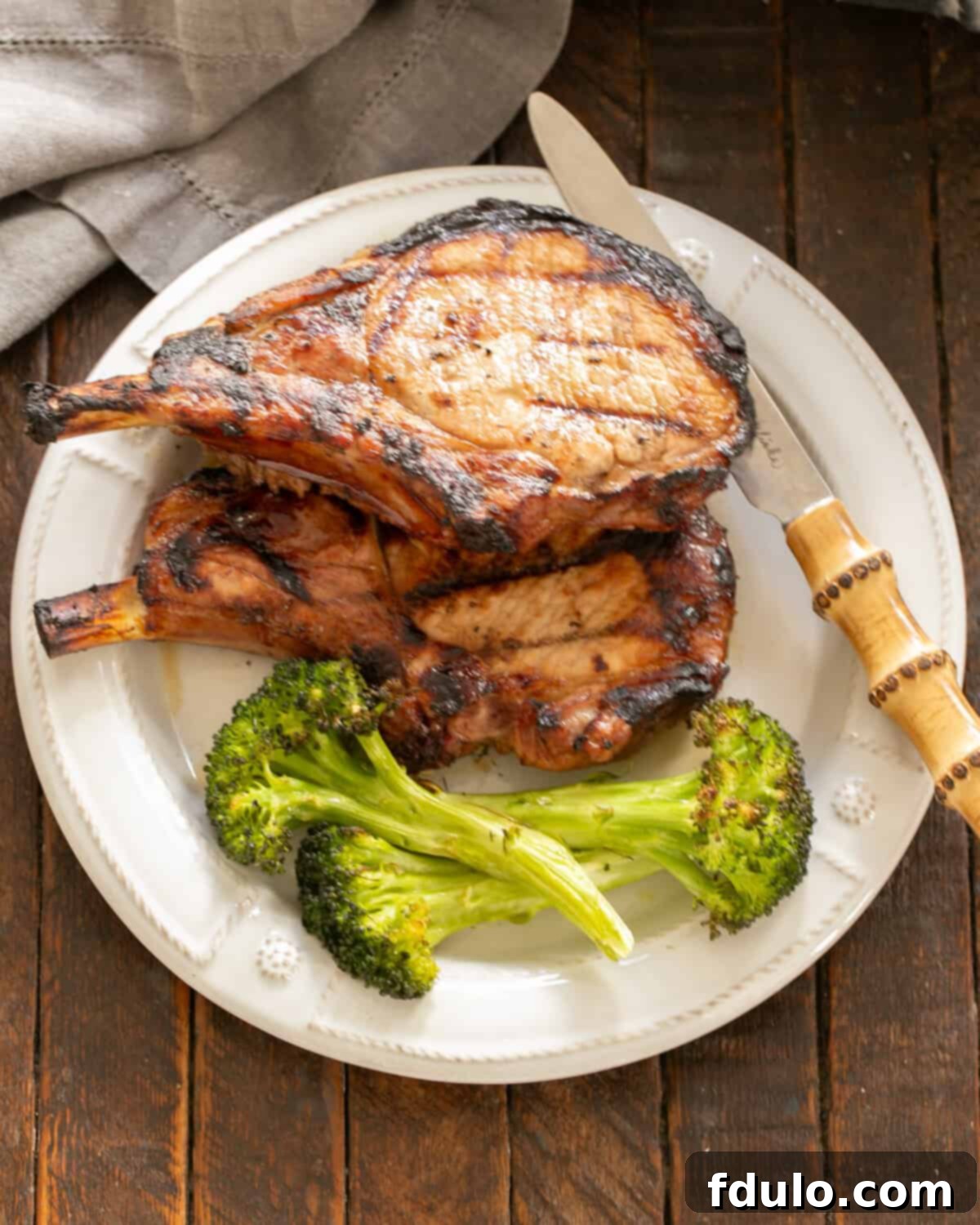 Grilled Pork chops on a white plate with broccoli.