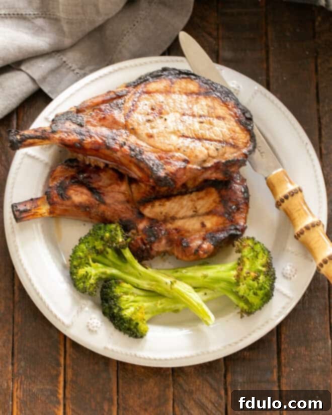 2 grilled pork chops and broccoli on a white dinner plate