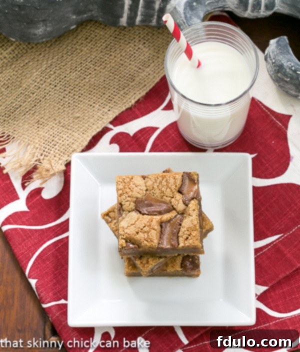 Biscoff Rolo Bars: The Perfect Sweet Treat with Milk Three Biscoff Rolo Bars artfully stacked on a square white plate, accompanied by a refreshing glass of milk, inviting you to indulge.