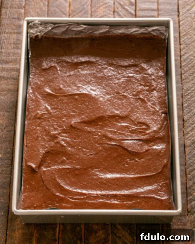 Brownie batter spread over the baked crust in the pan.