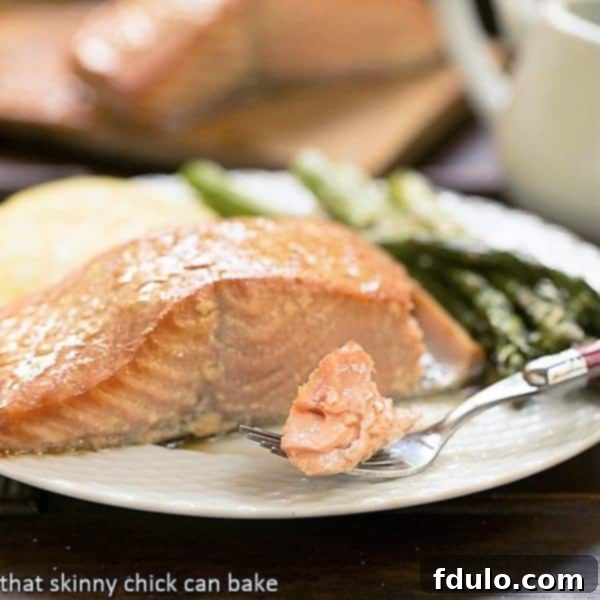 Enjoy an elegant and tasty seafood entree by plank grilling salmon with a simple yet effective marinade. A close-up of grilled cedar plank salmon on a plate, with a fork taking a bite, showing its flaky, moist texture.