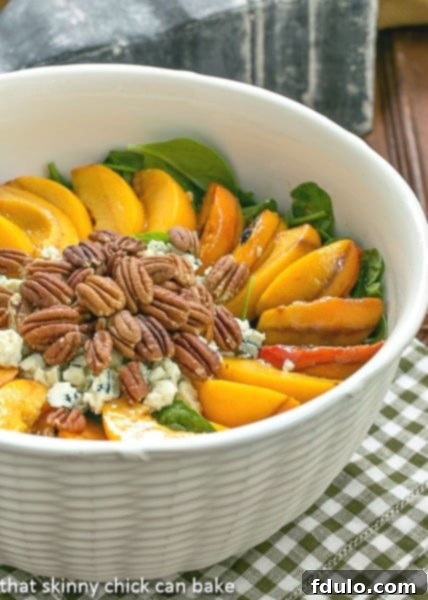 Spinach Salad with Grilled Peaches and Blue Cheese in an elegant white textured serving bowl, ready to be enjoyed.