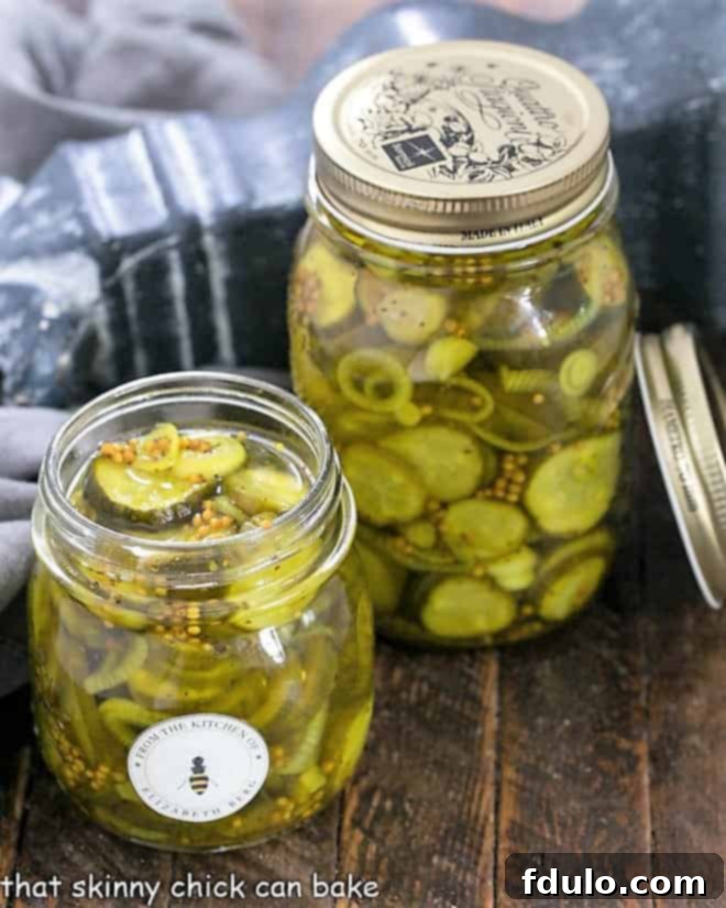 Two jars of Easy Bread and Butter Pickles, one without a lid, beautifully showcasing their vibrant yellow-green hue and crisp slices.