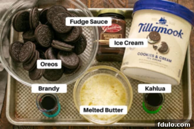 Arrangement of Chocolate Ice Cream Pie Ingredients on a baking sheet, including chocolate wafer cookies, butter, sugar, chocolate ice cream, Kahlua, brandy, and fudge sauce.