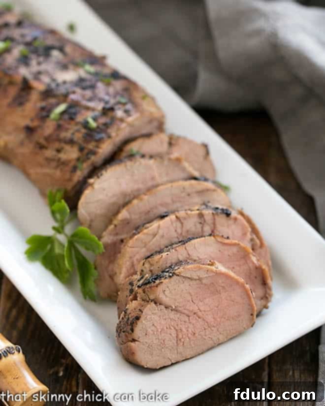 Whiskey Marinated Pork Tenderloin partially sliced on a white serving tray
