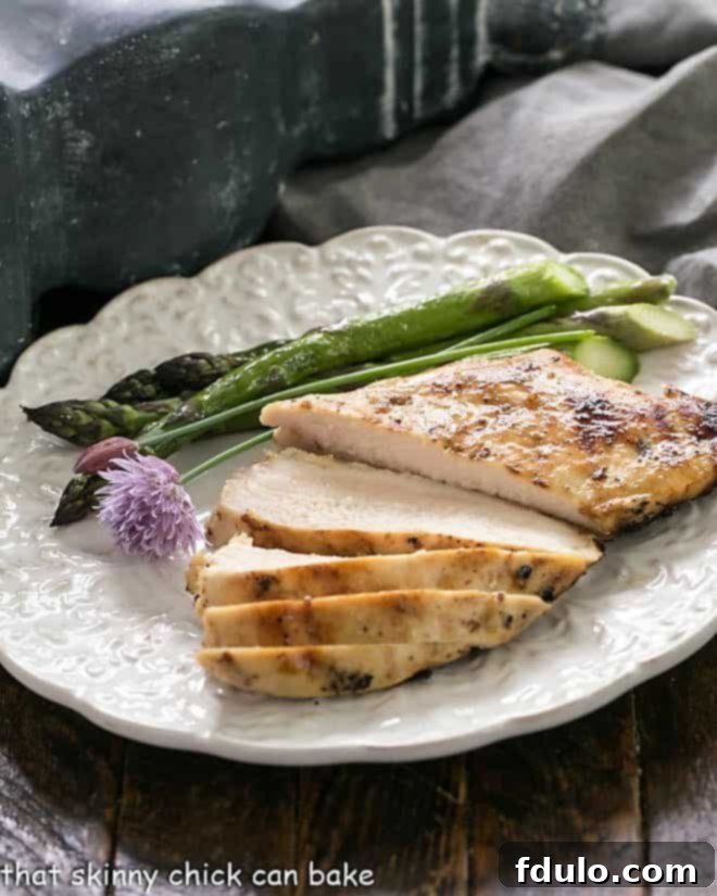 A sliced chicken breast on a white dinner plate with asparagus.