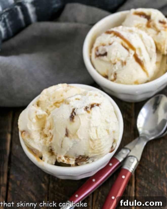 Two bowls of Vanilla Caramel Swirl Ice Cream, adorned with two red-handled spoons, showcasing the enticing swirls of caramel throughout the creamy vanilla base.