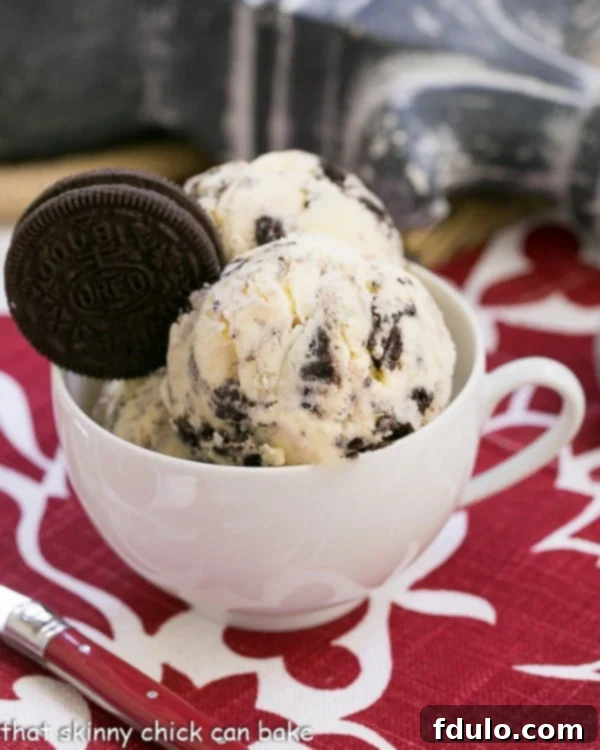 Scoops of homemade Oreo Ice Cream in a vintage teacup, garnished with a whole Oreo cookie.