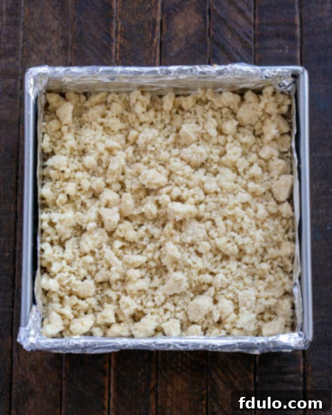 Golden Caramel Squares 10 Remaining dough is crumbled over the caramel layer in the baking pan using fingers.