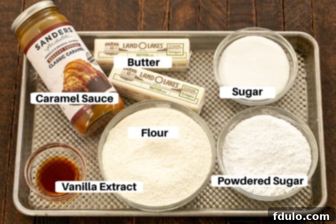 Golden Caramel Squares 3 Individual ingredients for Caramel Butter Bars laid out on a metal baking sheet, including butter, sugars, flour, vanilla extract, and a jar of caramel sauce, each with a small label.