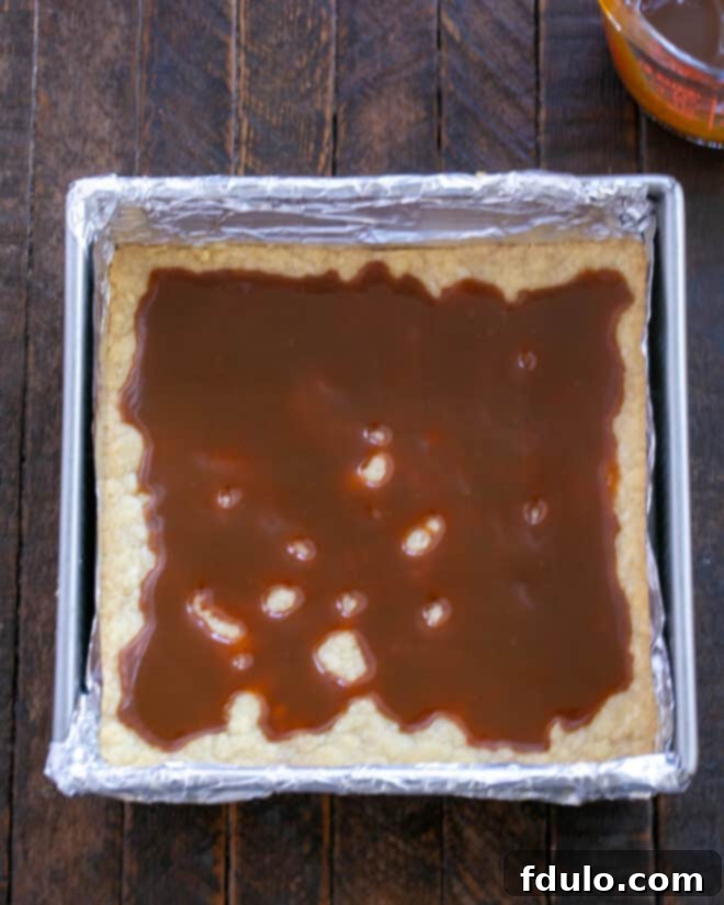 Golden Caramel Squares 8 Caramel sauce is being drizzled over the hot, baked shortbread crust in a baking pan.