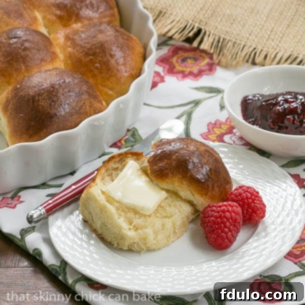 Brioche Dinner Rolls on a white plate with a pat of butter.
