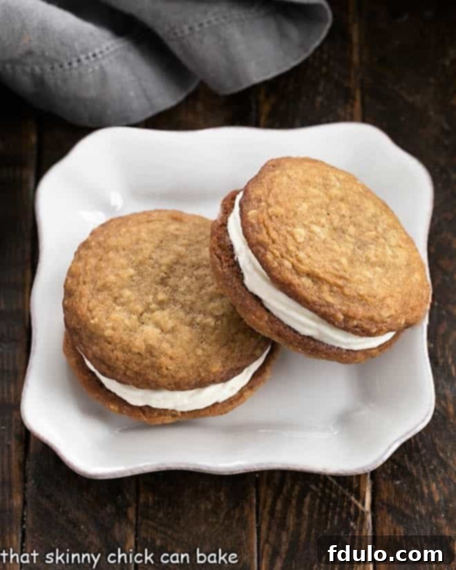 Copycat Little Debbie Oatmeal Creme Pies - Deliciously oversized, chewy oatmeal cookies filled with a dreamy, creamy center. Overhead view of two decadent Oatmeal Creme Pies presented on a square white plate, showing off their generous filling.