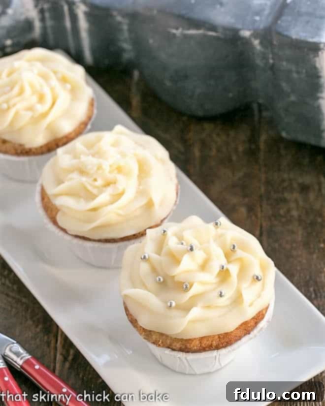 A rectangular white tray filled with an assortment of beautifully frosted vanilla cupcakes, some with sprinkles, showcasing their tender texture and creamy frosting.
