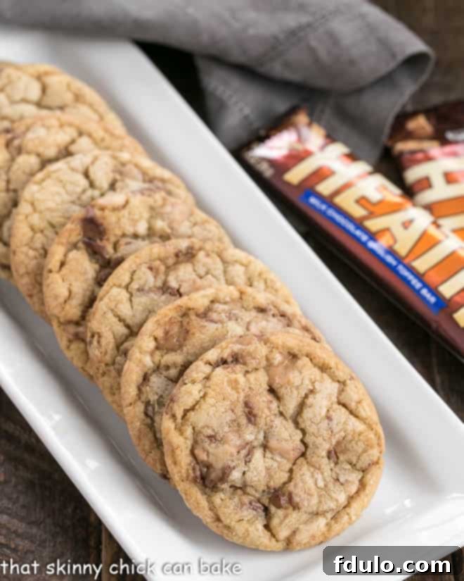 Perfectly baked Brown Butter Toffee Cookies cooling on a white tray, showcasing their golden edges and delicious toffee bits.