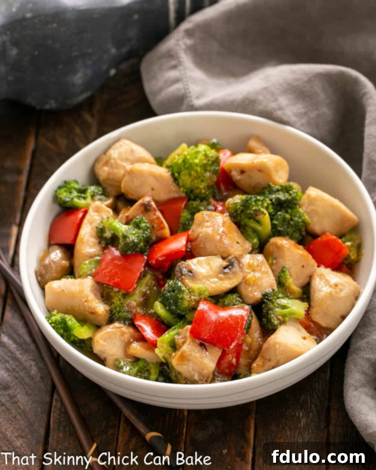 A beautifully presented Chicken, Broccoli, and Bell Pepper Stir Fry in a pristine white ceramic serving bowl, garnished and ready to be enjoyed.