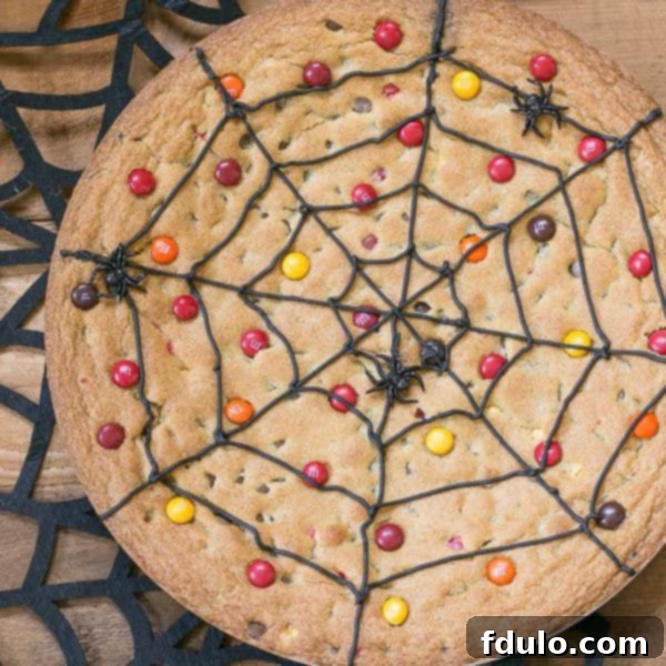 Spiderweb Cookie Cake topped with M&M's on a felt spiderweb, ready for Halloween festivities.